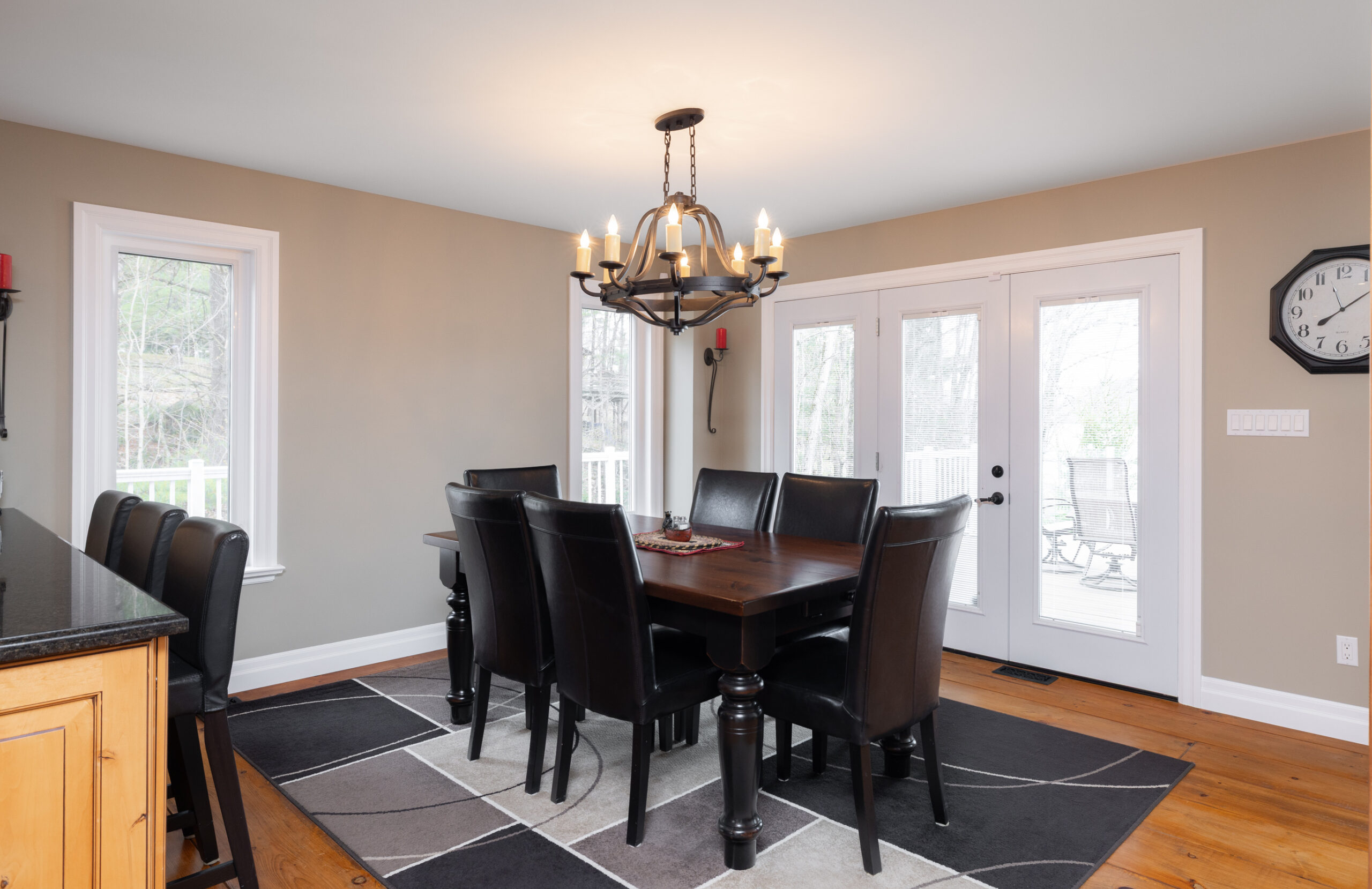 Dining room with a wooden table, black leather chairs, and a chandelier.