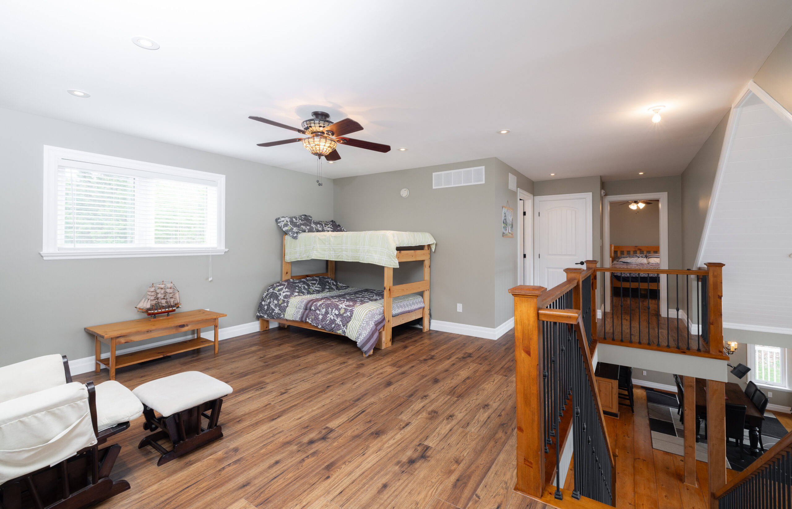 Open bedroom at the top of a staircase with bunk beds.