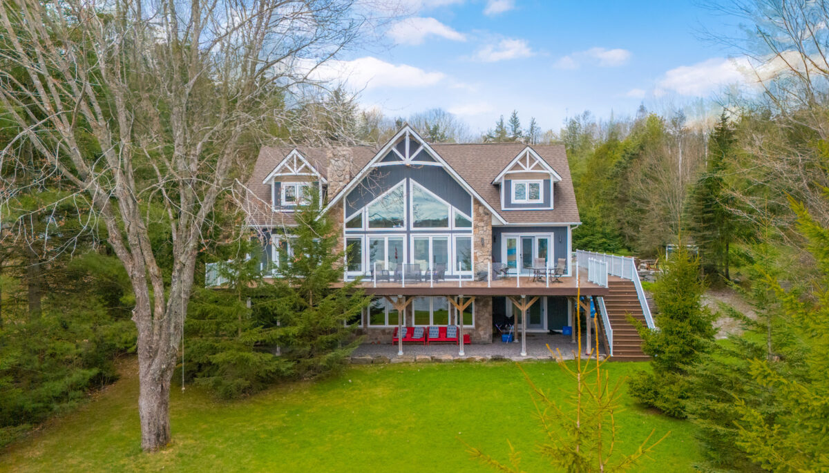 Cottage with large windows and vaulted roofs on a grass lawn.