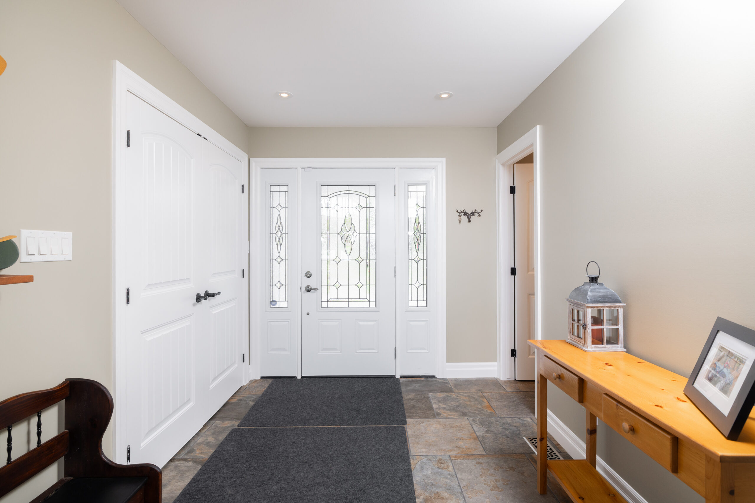 Interior of home entrance with a front door, closet, and side table.