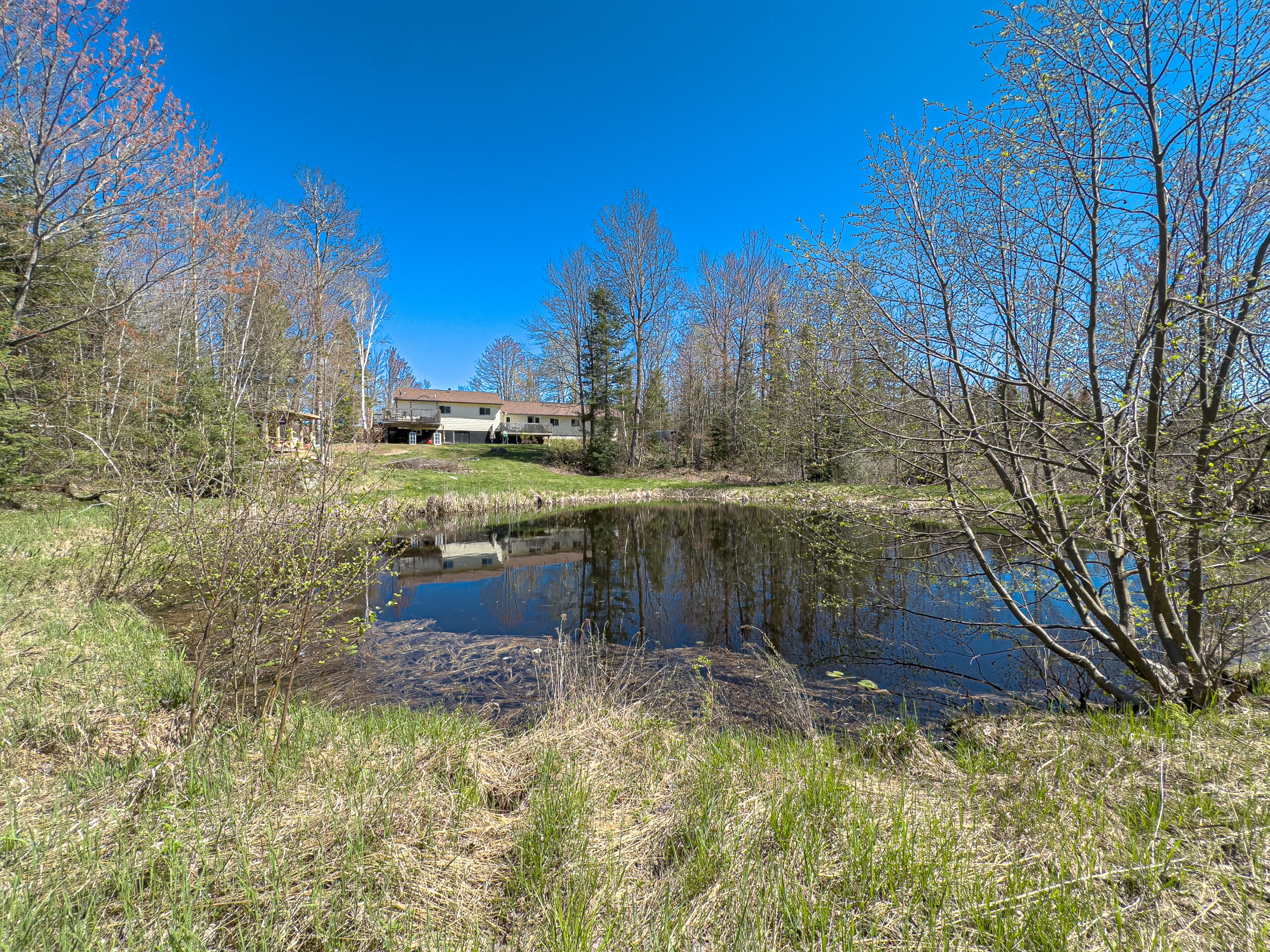 A blue pond behind a cottage in a grassy area
