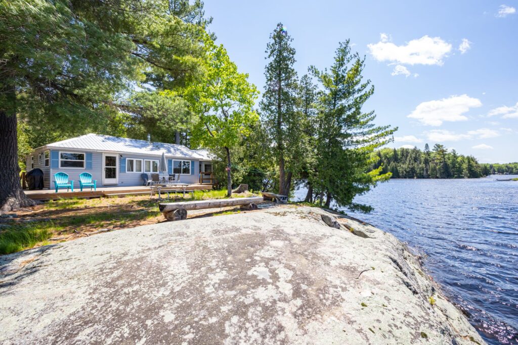 View of Bear Lake cottage nestled beside large granite outcrop at the water’s edge