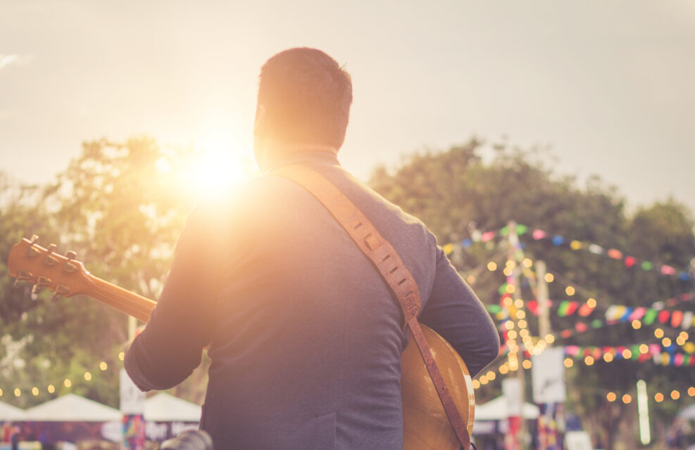 Man playing guitar at an outdoor live music event