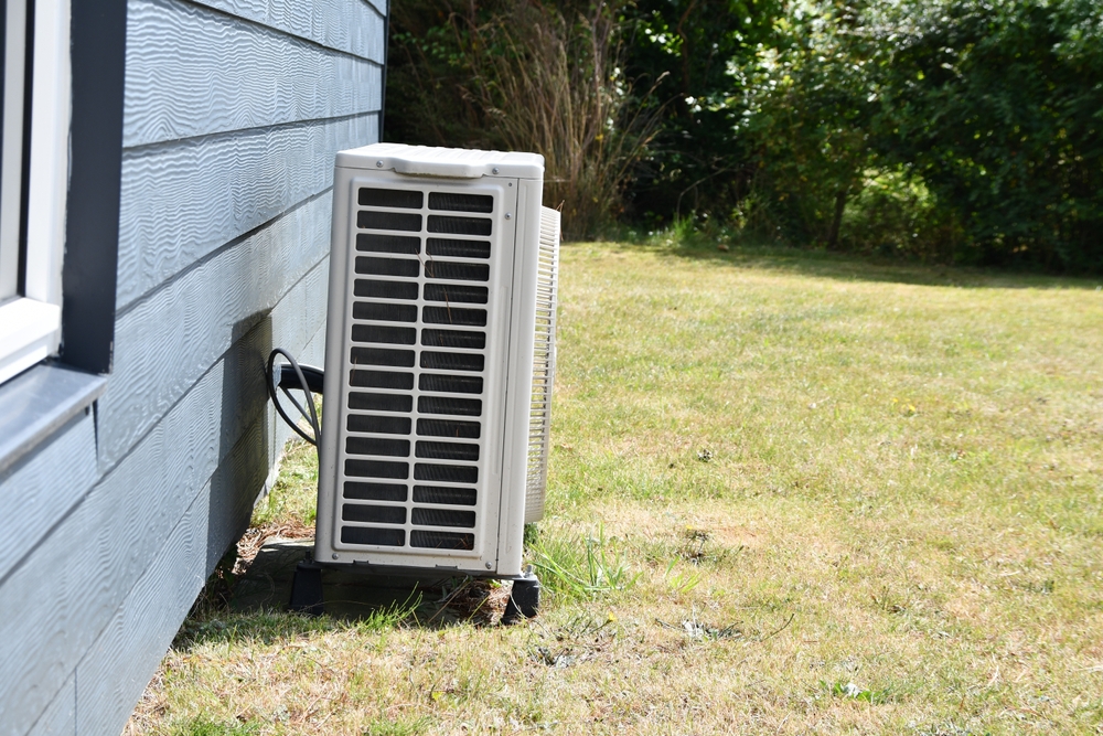A heat pump device that heats a building (or part of a building) by transferring thermal energy from the outside using the refrigeration cycle installed on a wooden house in summer day
