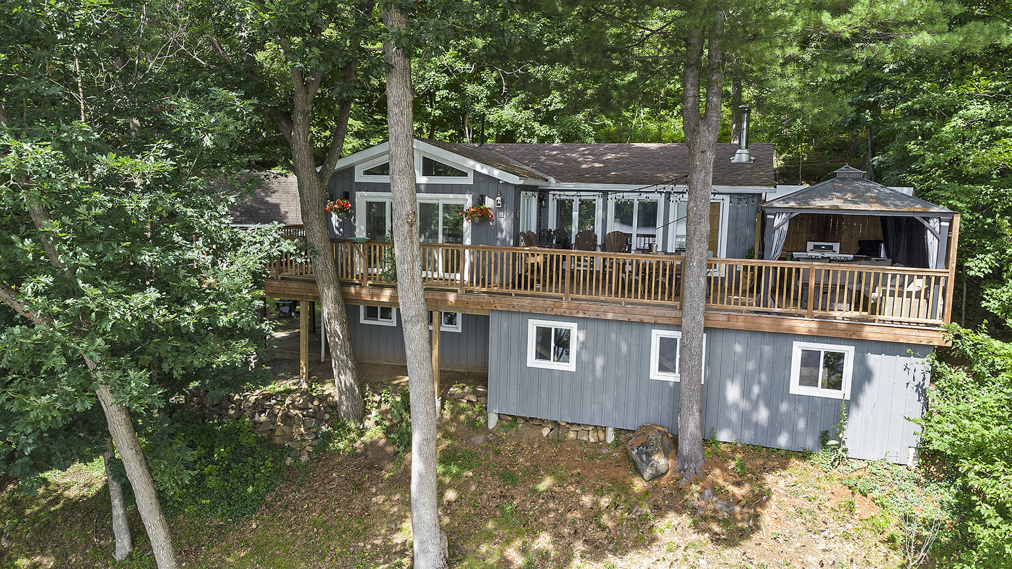 Elevated view of the main cottage nestled among mature trees with a wraparound deck
