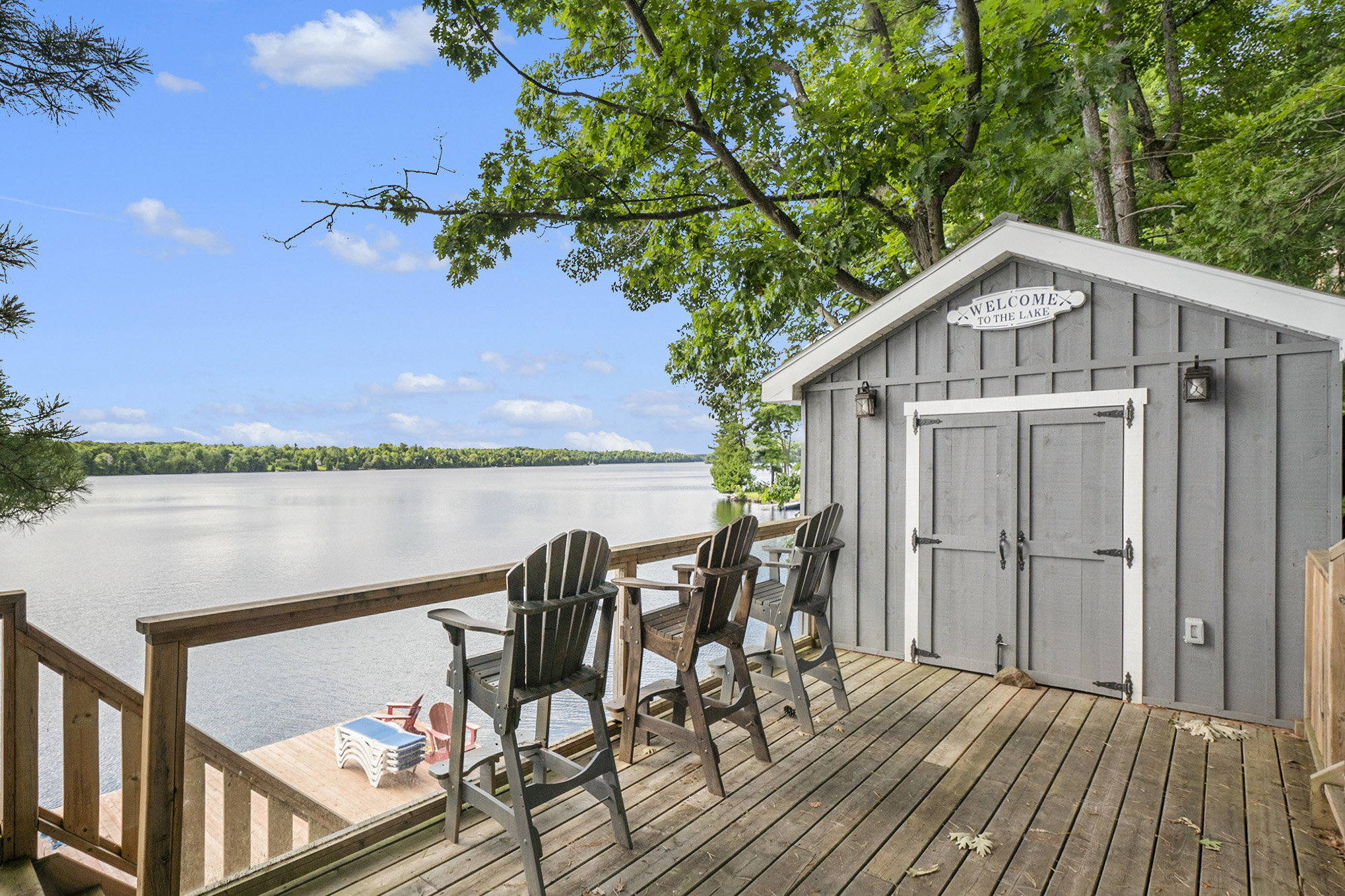 Lakeside storage shed with hydro and bar setup, next to dock seating area with lake views
