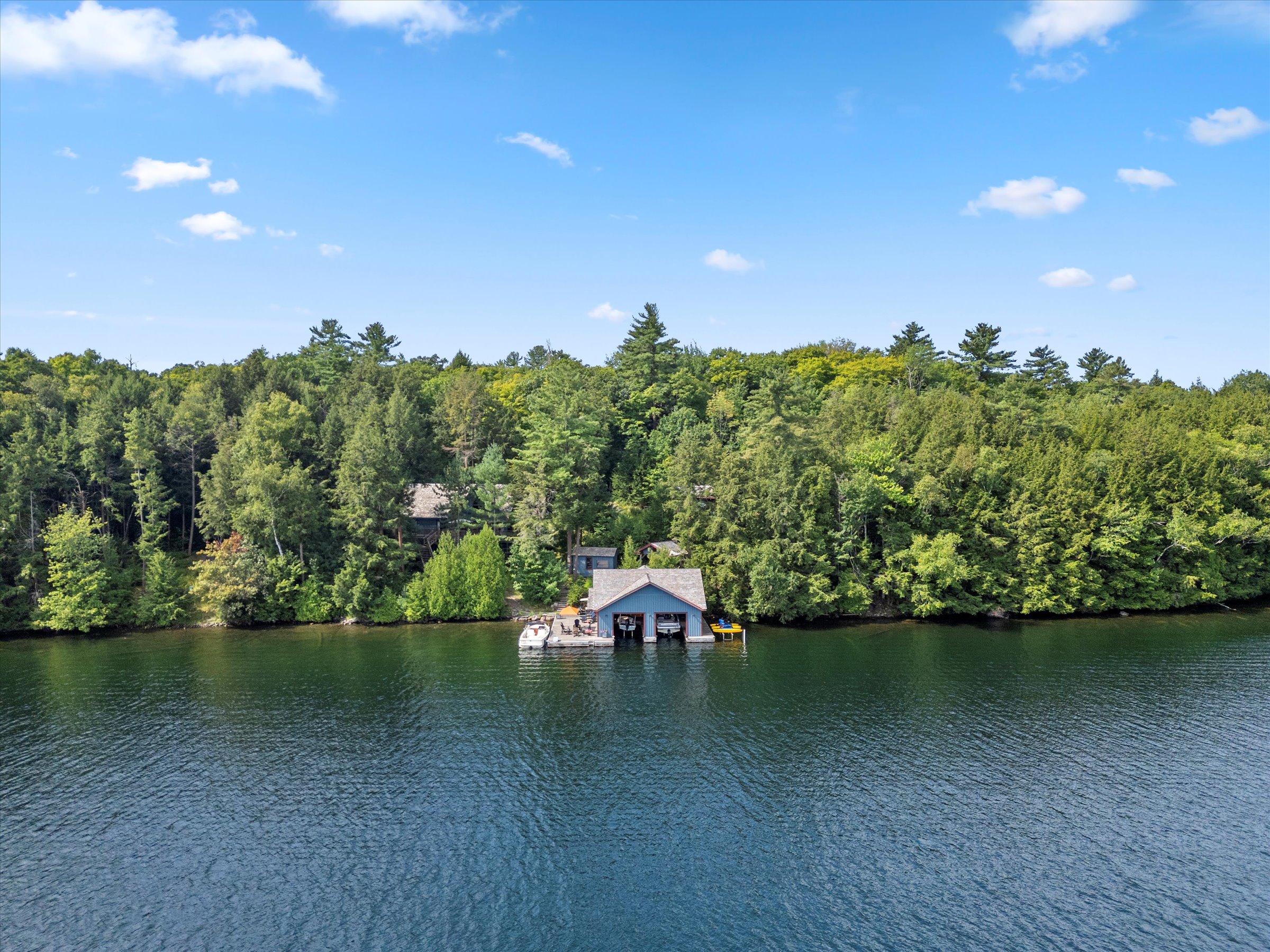 Wide-angle view of the island compound showing the shoreline and multiple buildings surrounded by trees
