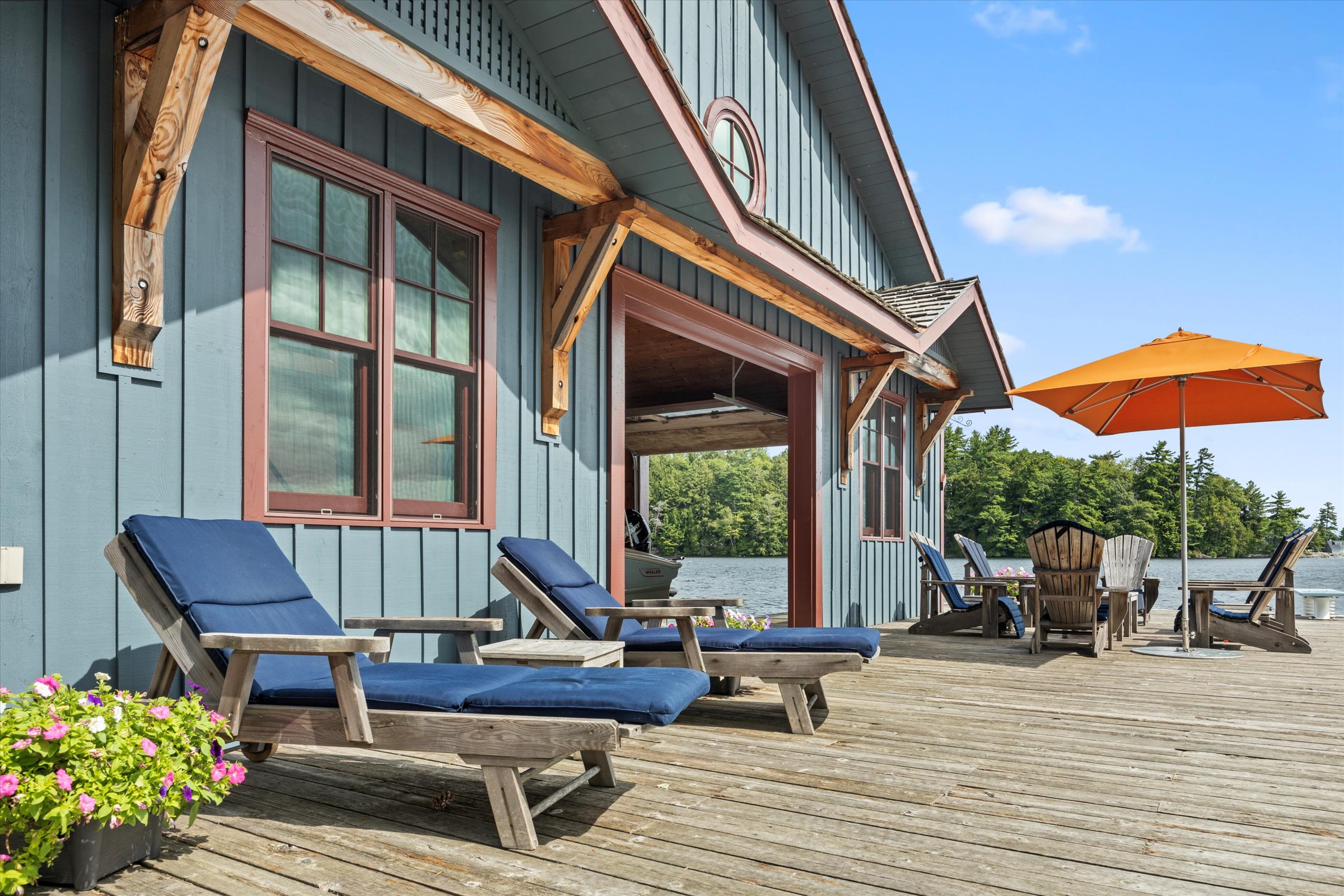 Sunny boathouse deck with outdoor lounge chairs and umbrella, perfect for lakeside relaxation