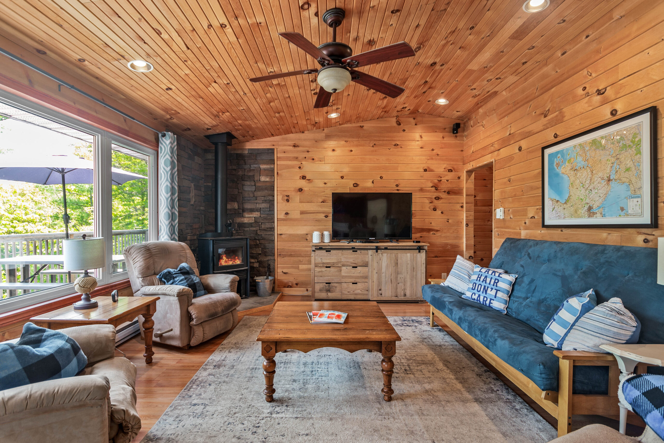 A wood-paneled room with a blue couch facing bright windows