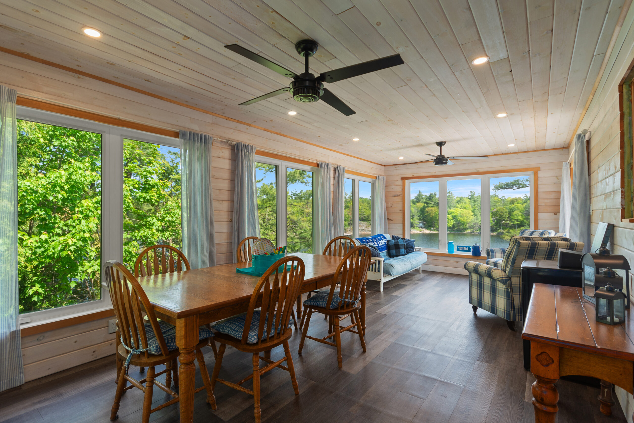 In a bright sunroom, a wood dining table next to a blue sitting area