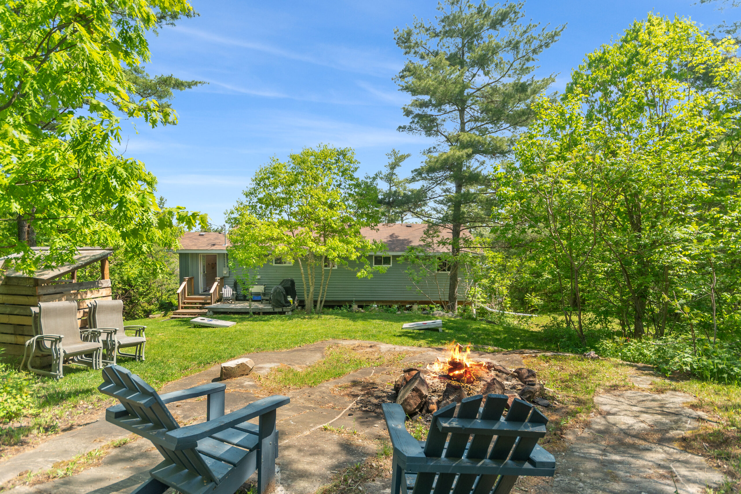 Two Muskoka chairs by a fire pit on the cottage property