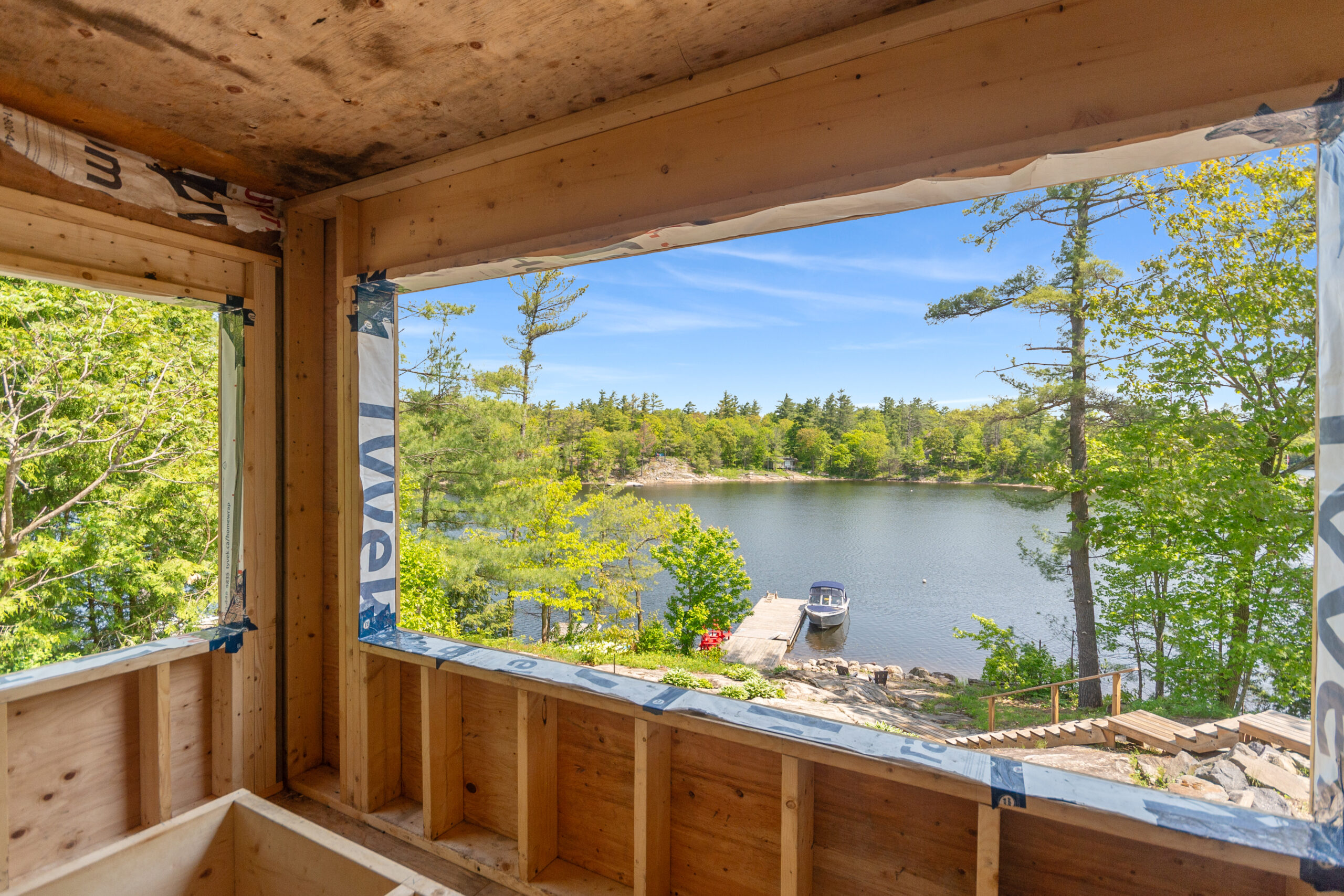 An unfinished wood room with an open window looks out onto the lake