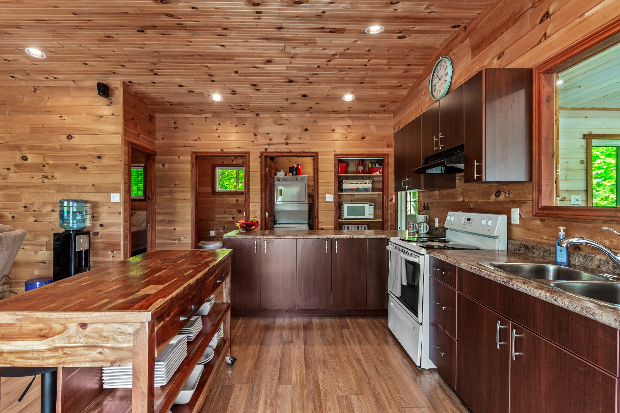 A dark wood-paneled kitchen with a white oven facing the kitchen island