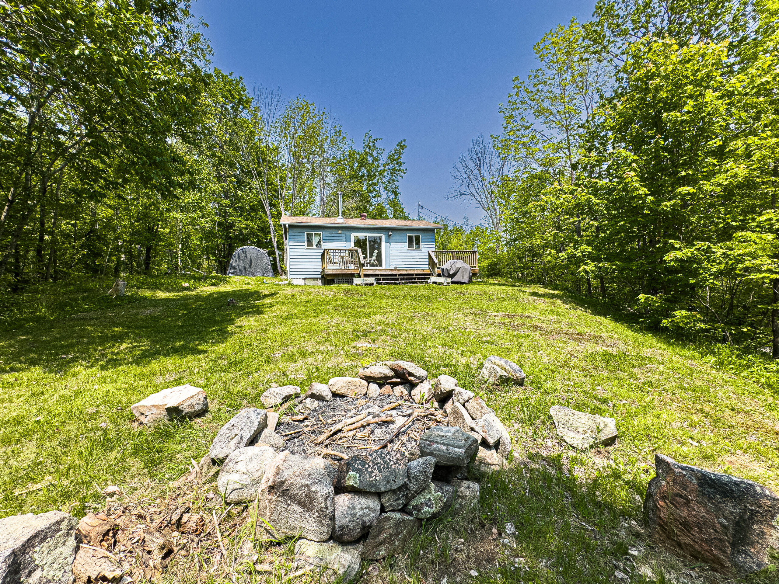 A fire pit with a blue cottage in the background