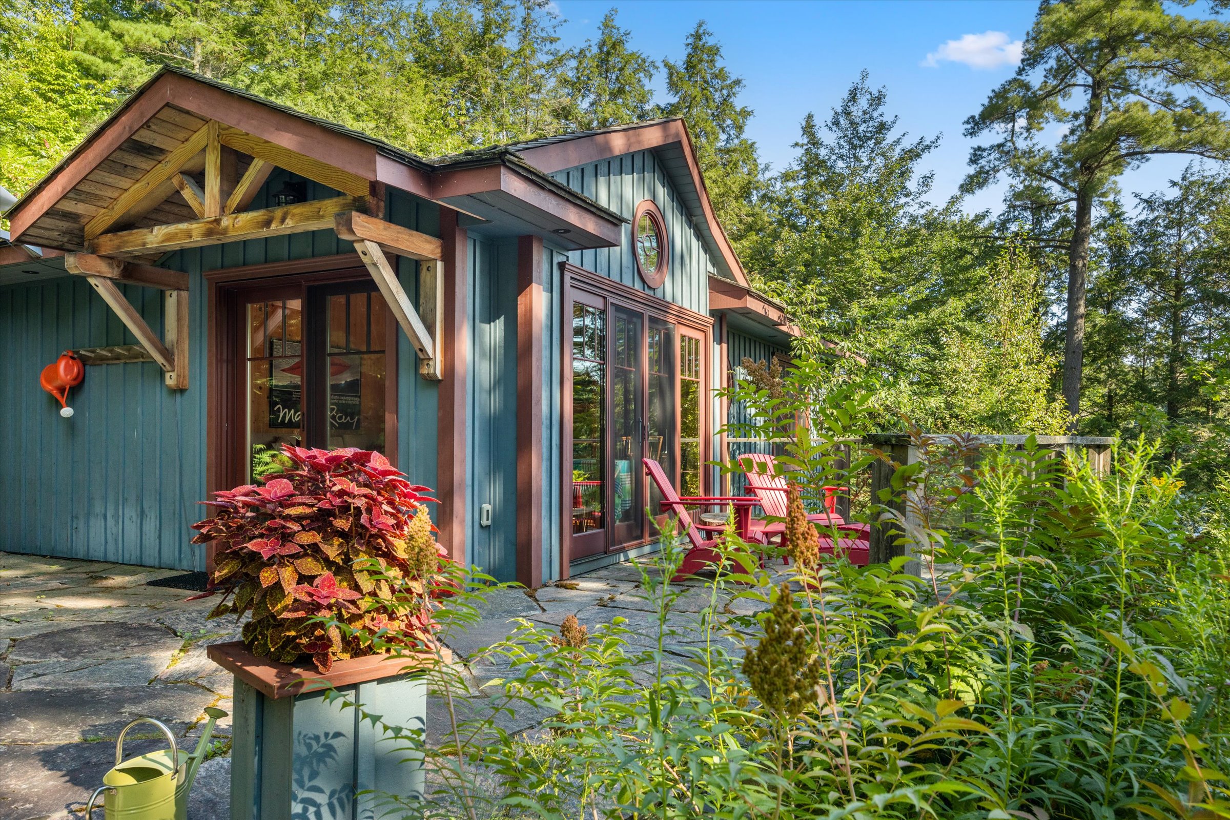 Rustic guest cottage exterior surrounded by mature greenery and Muskoka landscaping