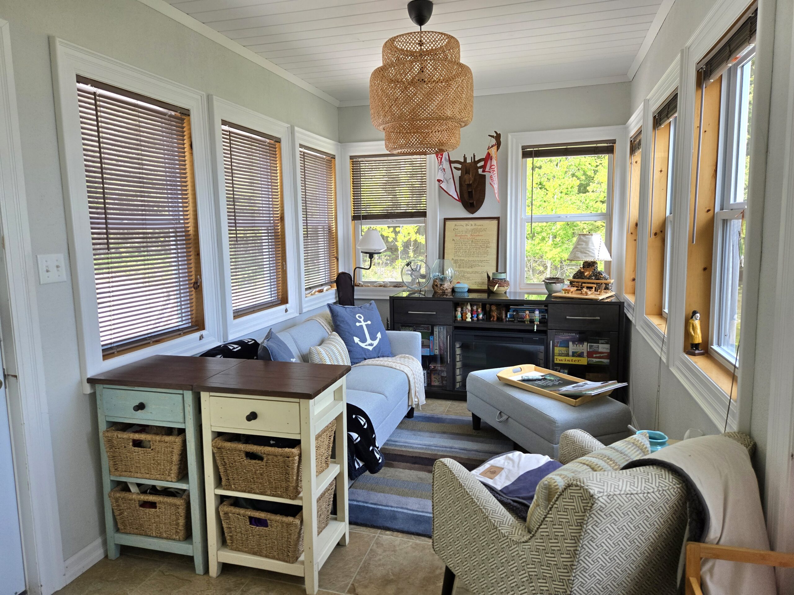 Window-lined sunroom with casual seating and woven pendant light