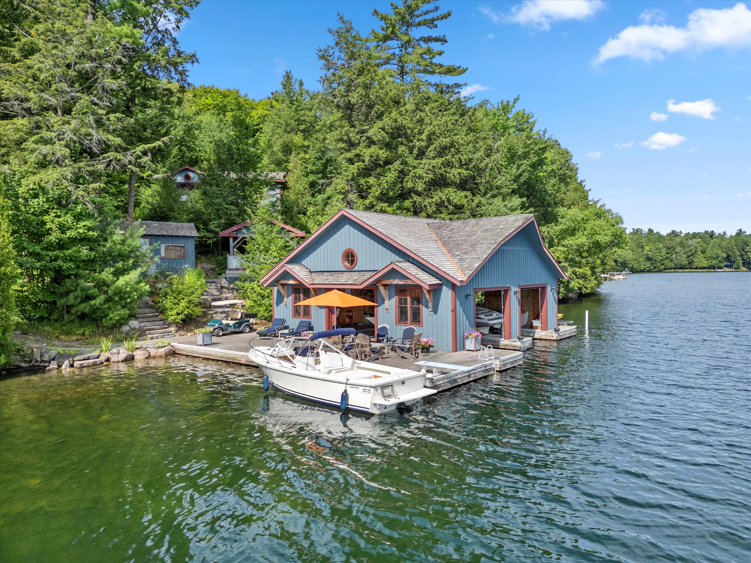Two-slip boathouse nestled along a quiet section of shoreline, surrounded by trees and calm water