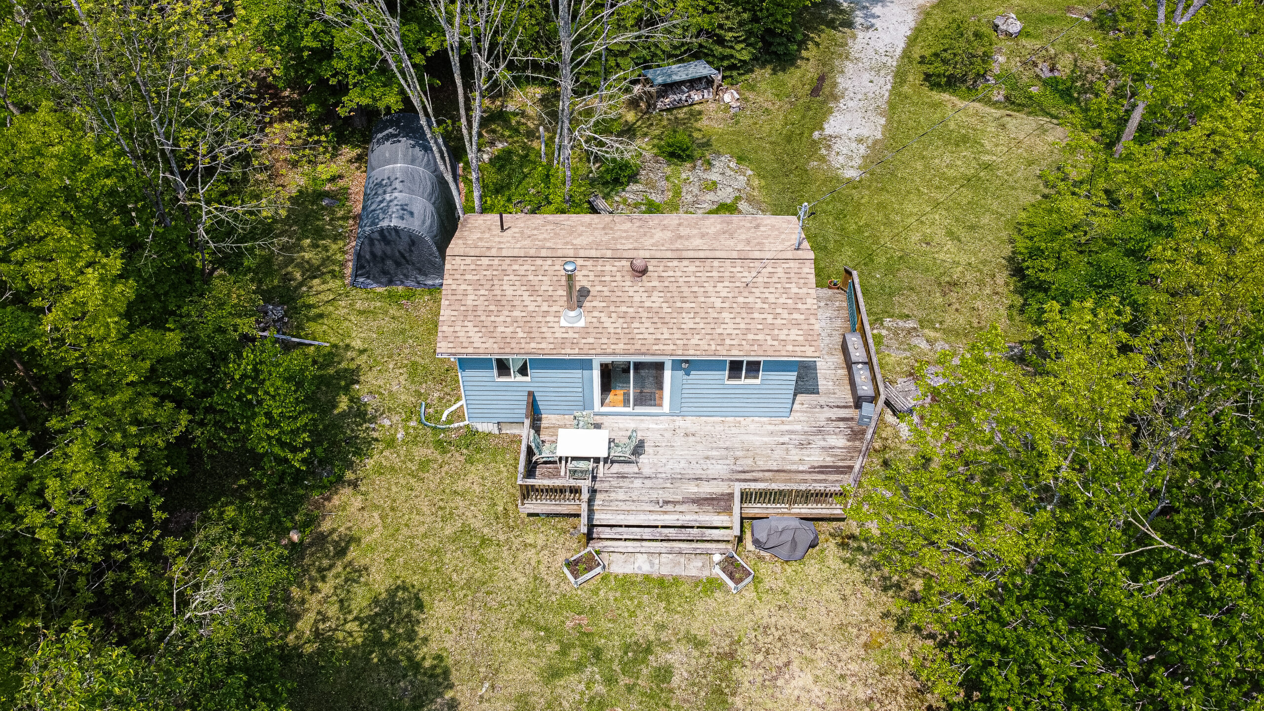 Aerial view of a small blue cottage with a wood deck