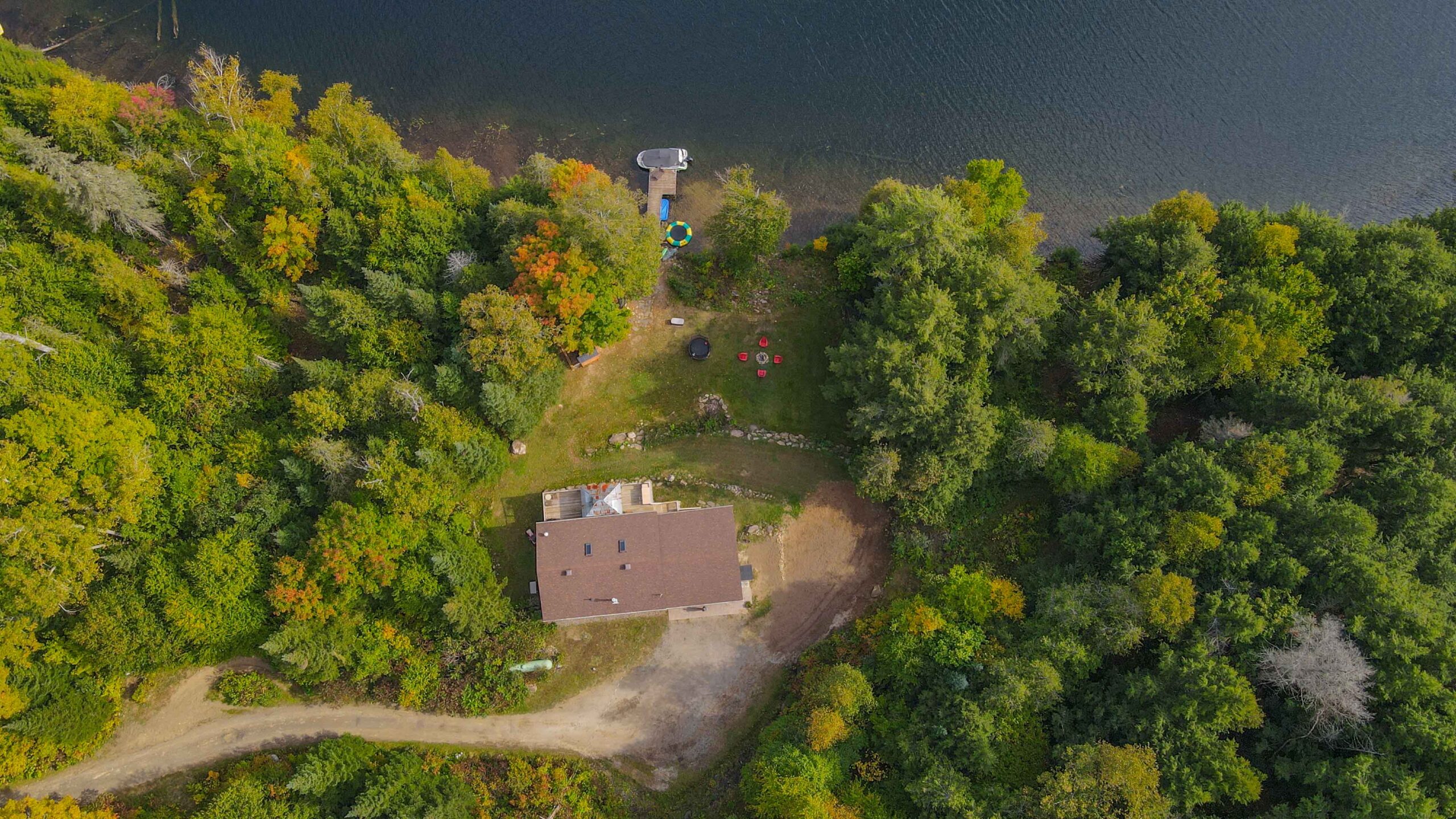 Overhead drone view showcasing the cottage nestled among trees with direct waterfront access.