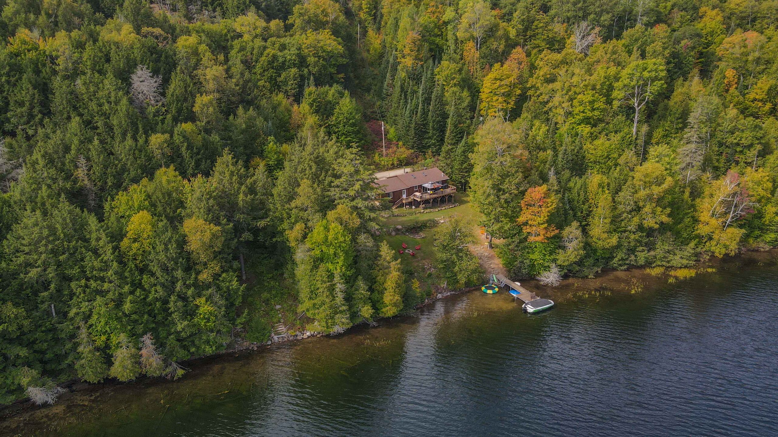 Elevated drone perspective of the cottage on the tree-lined shores of Trout Lake.