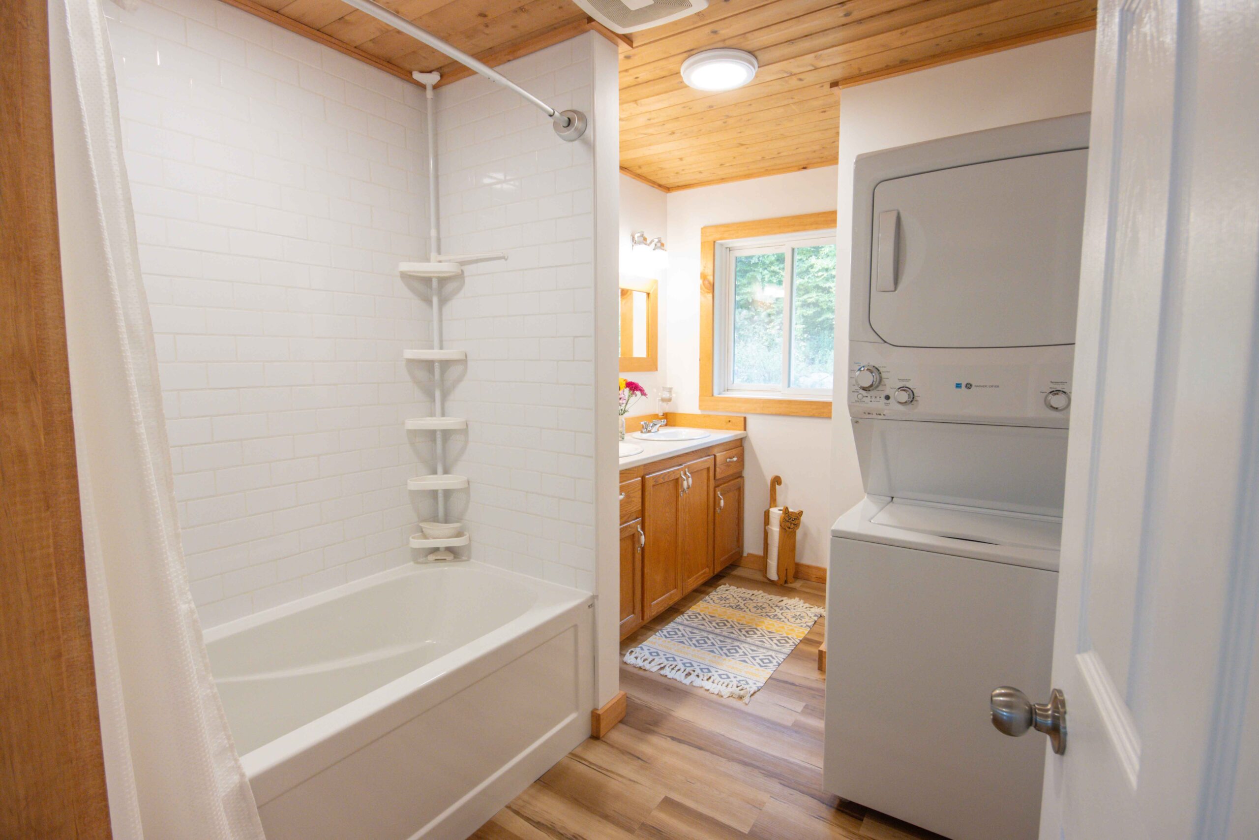Full bathroom with tub/shower combo and stacked washer-dryer.