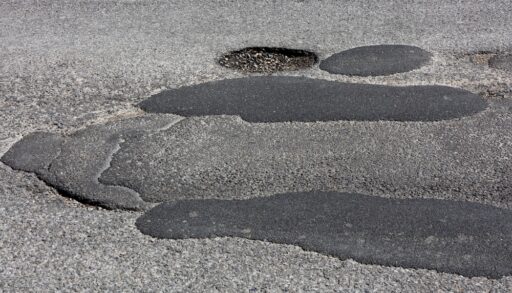 Horizontal view of badly patched asphalt pavement and pothole on a road in Canada