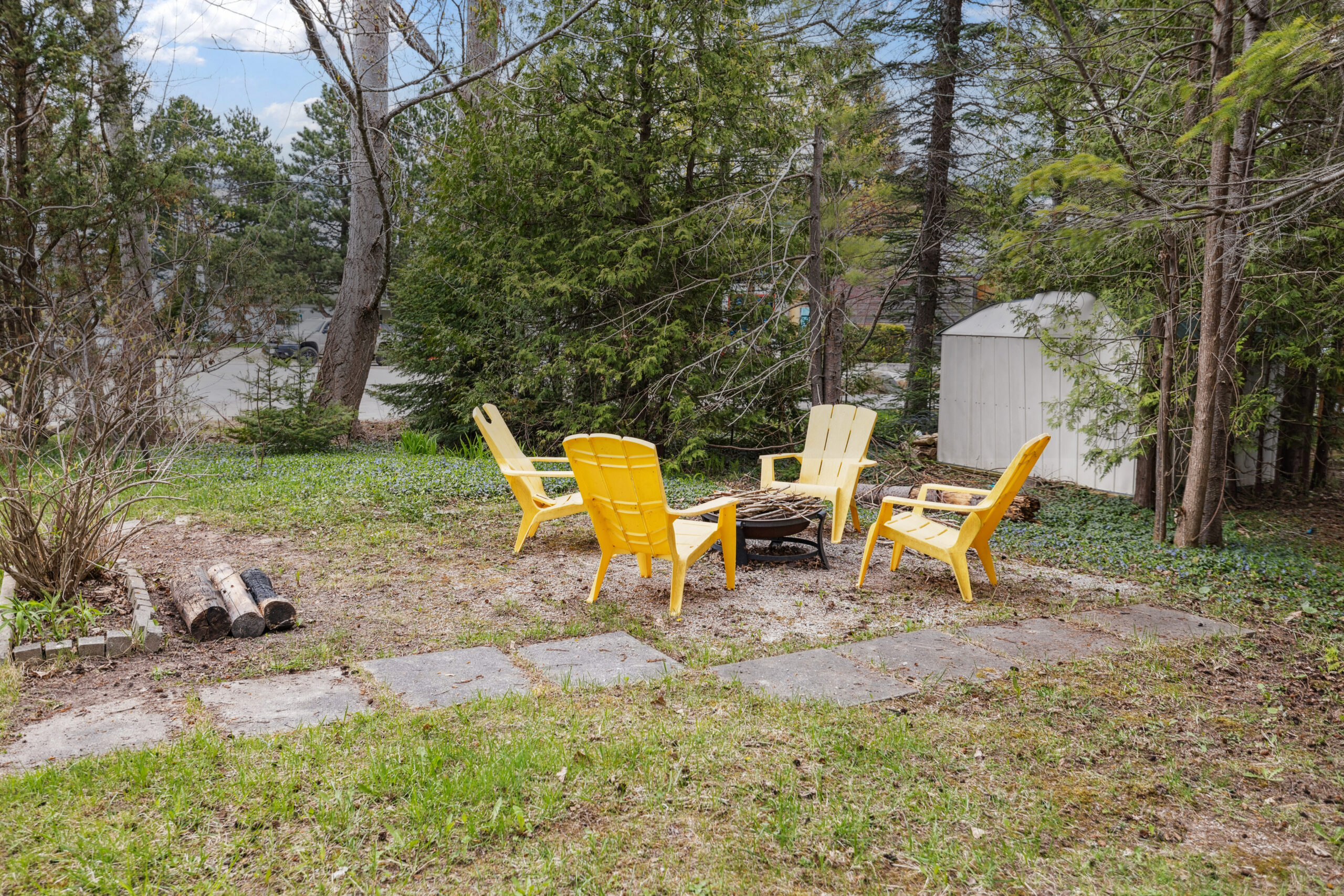 Four yellow Muskoka chairs around a fire pit