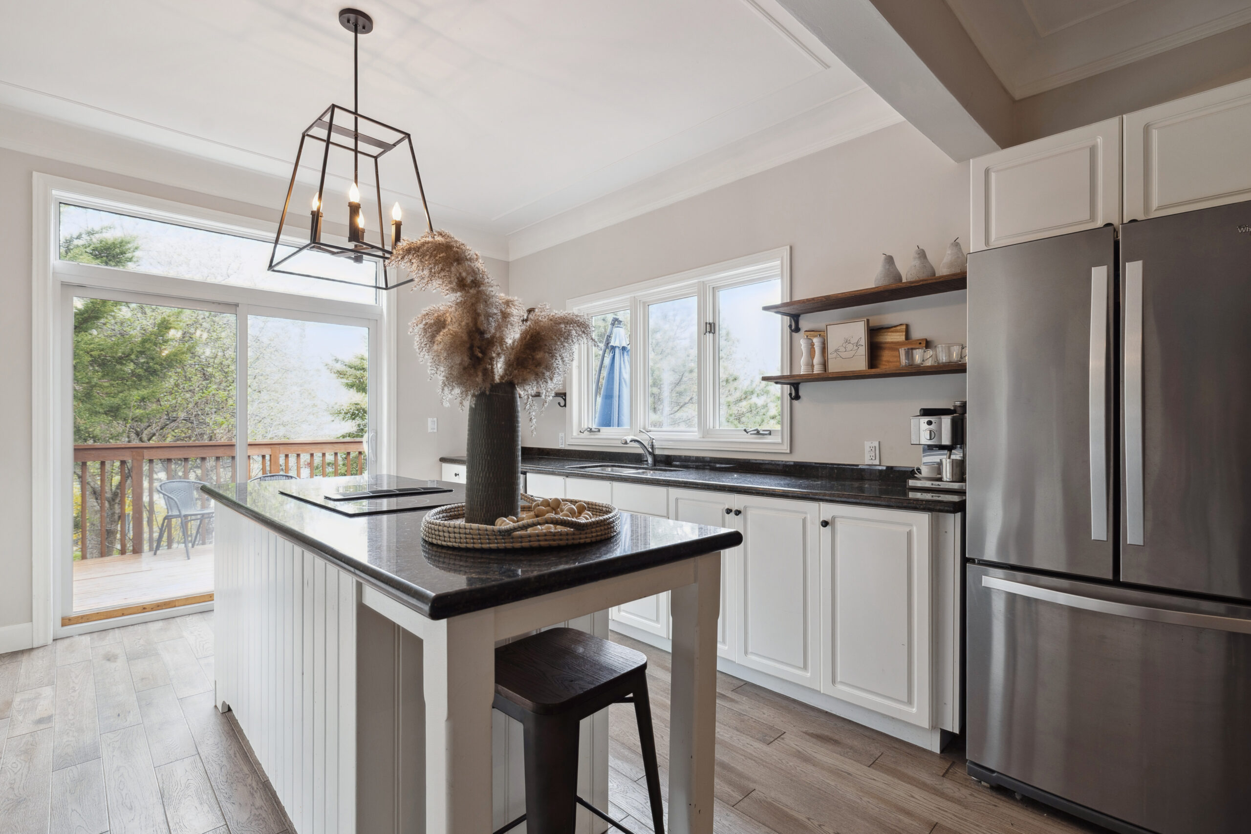 A white kitchen island with dark countertops in a white kitchen
