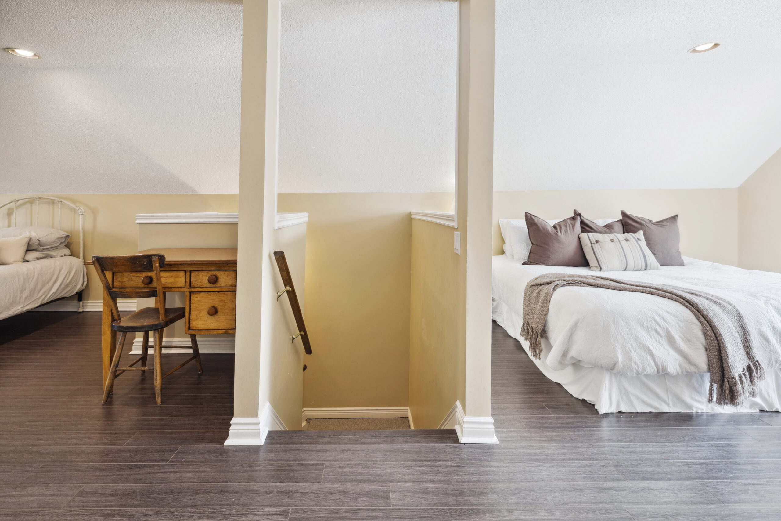 Steps lead up to a space with dark wood floors and beds on either side