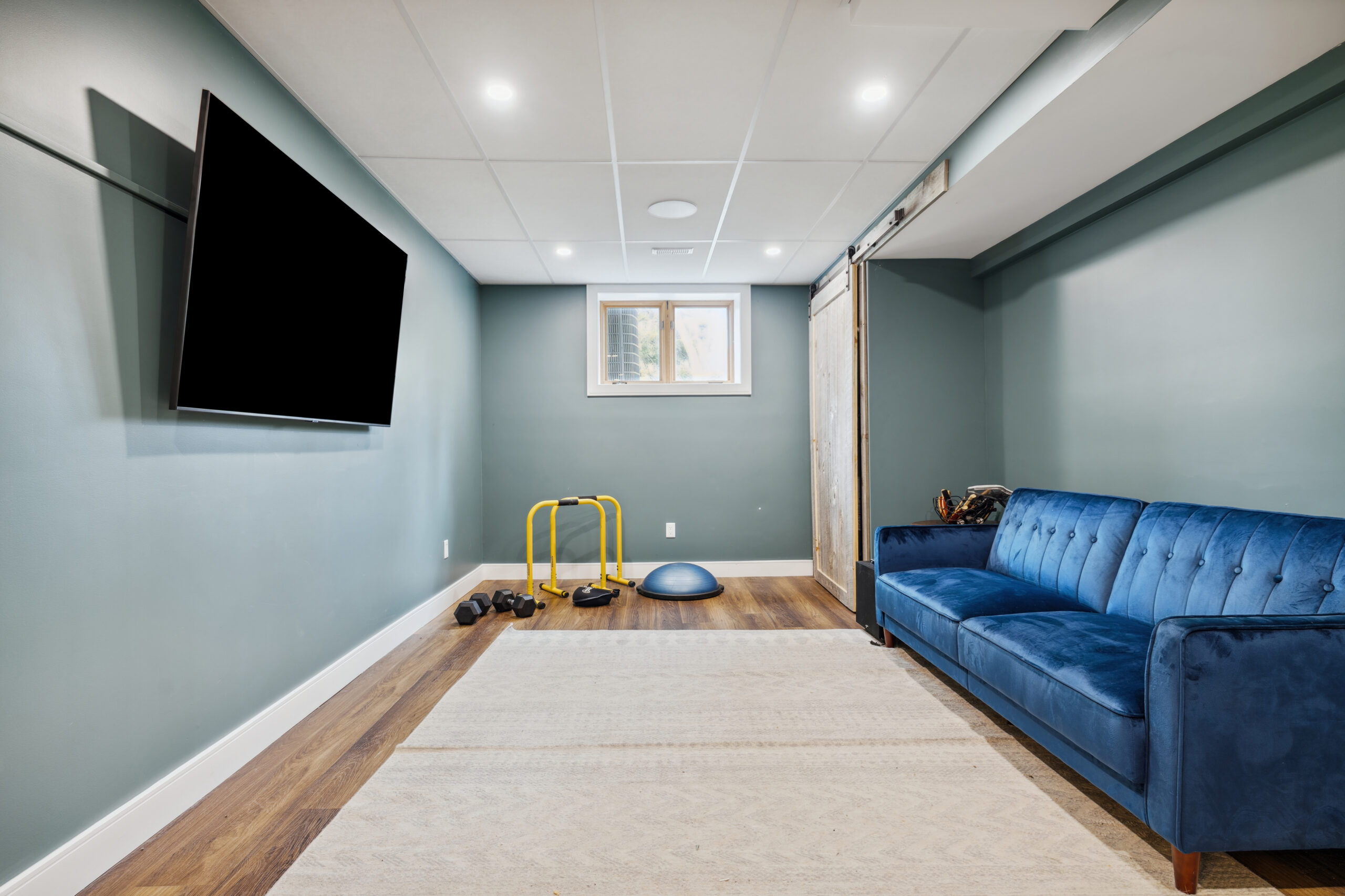 A blue couch faces a wall with a TV mounted in a blue room