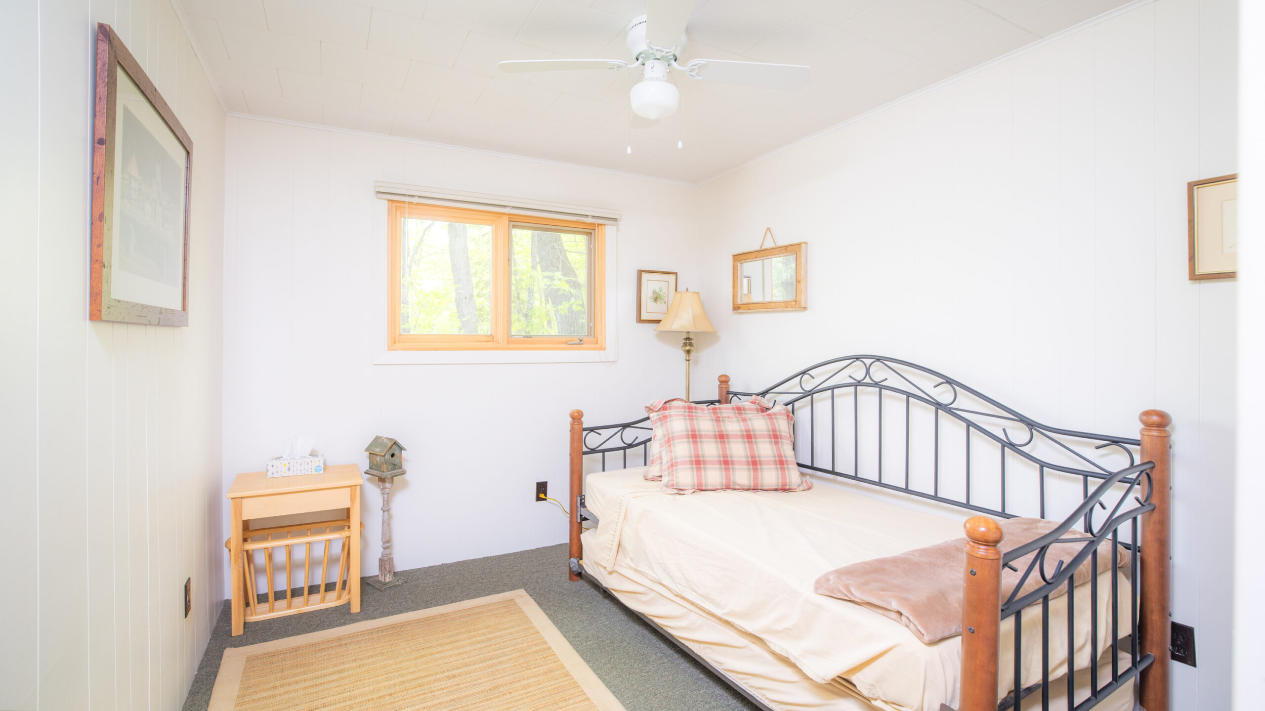 A white day bed in a dark metal frame in a white room