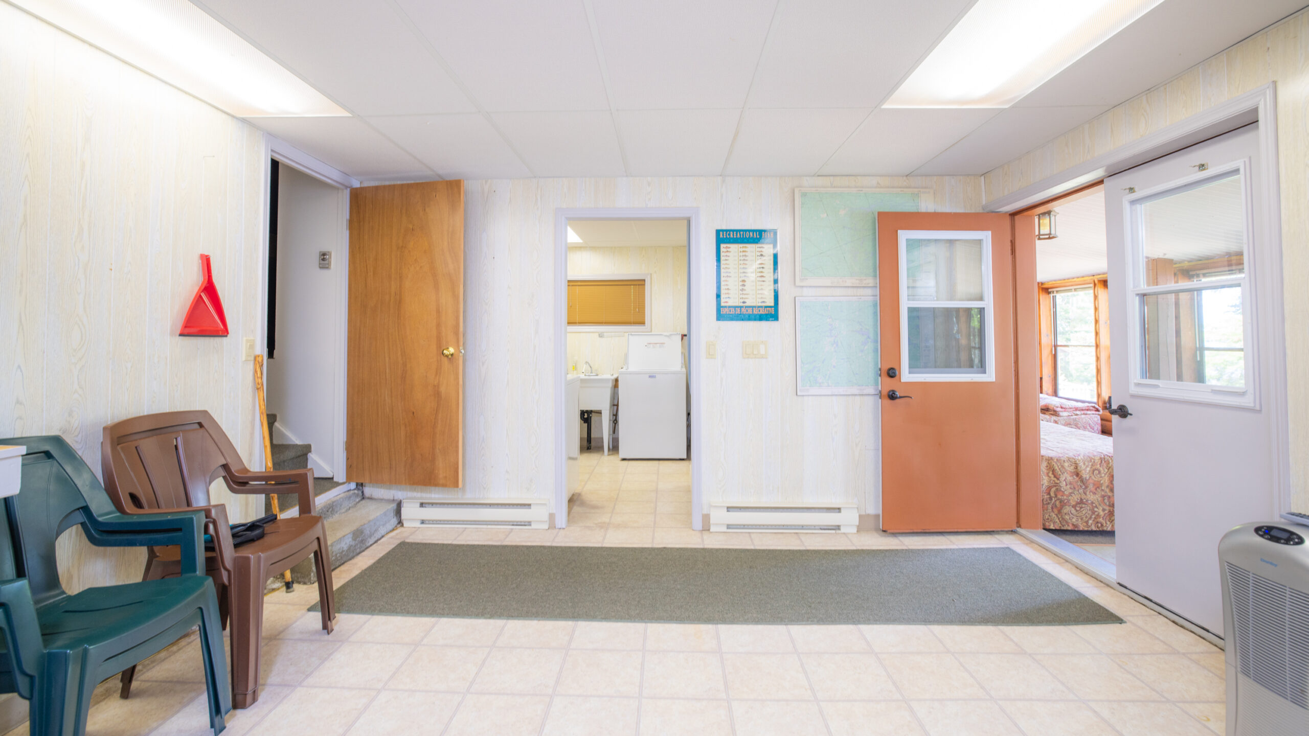 A white room with white tiles and a partially visible unfinished laundry area
