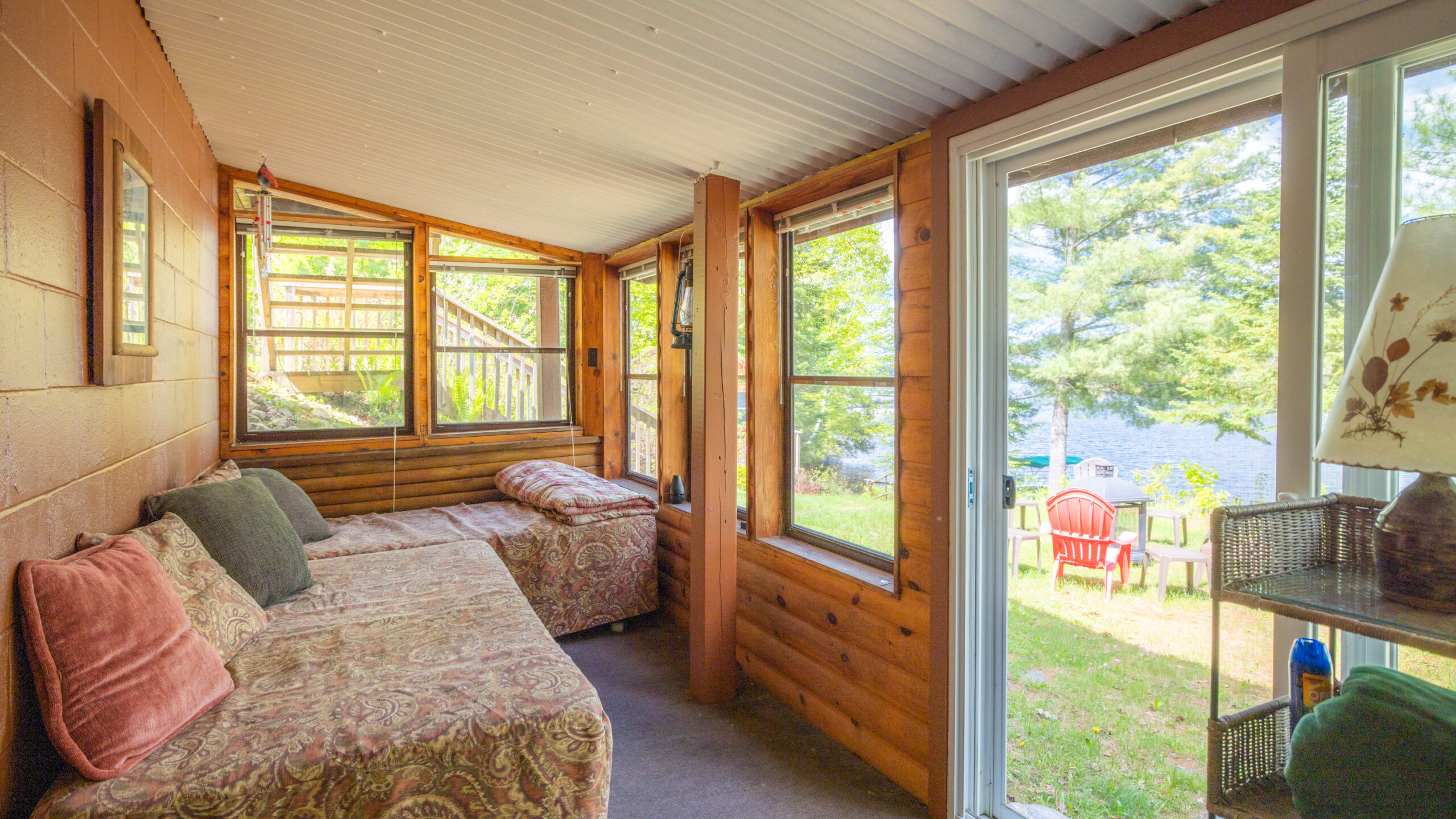 Floral couches in a wood-paneled sunroom with the door open to the yard