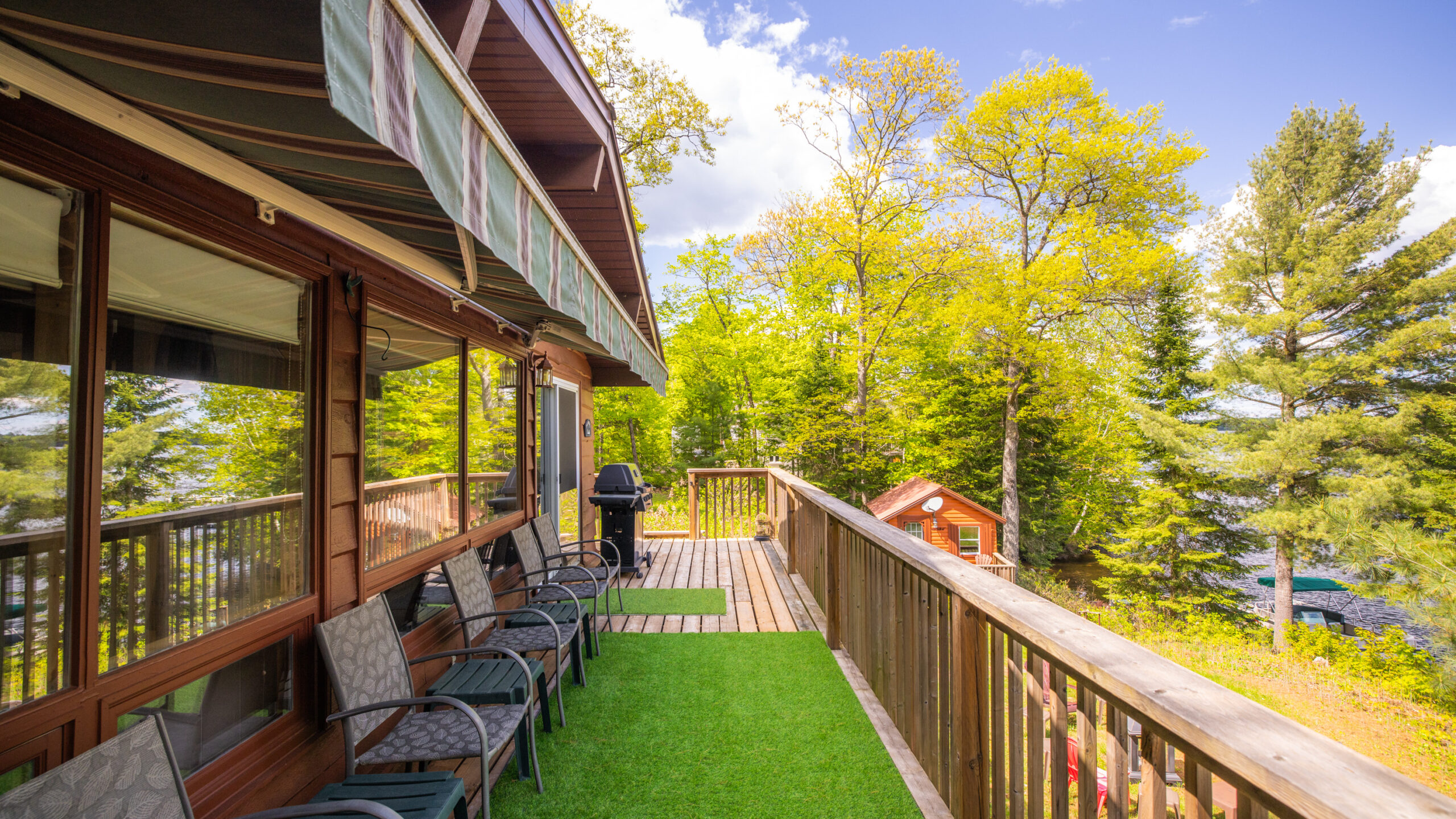 Lawn chairs are set up on fake turf on a cottage balcony