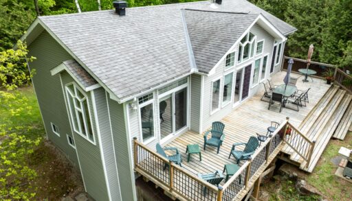 A beige-green paneled cottage with a spacious deck