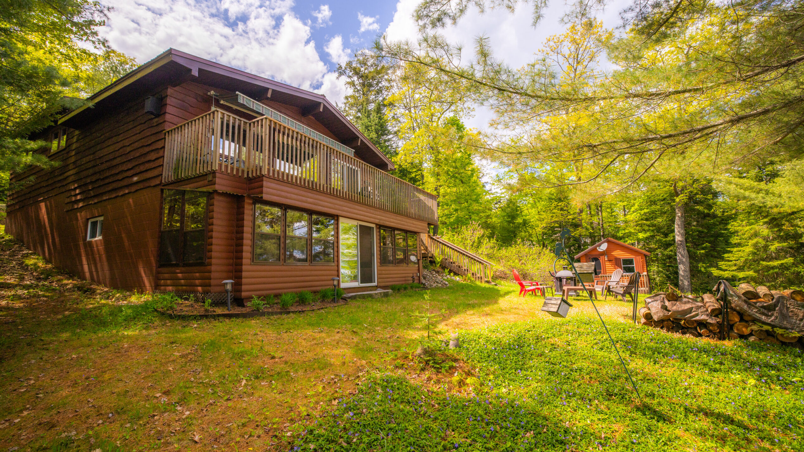 A two-level dark brown cottage on a grassy lawn