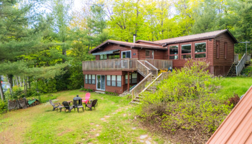 A two-level brown paneled cottage in the forest