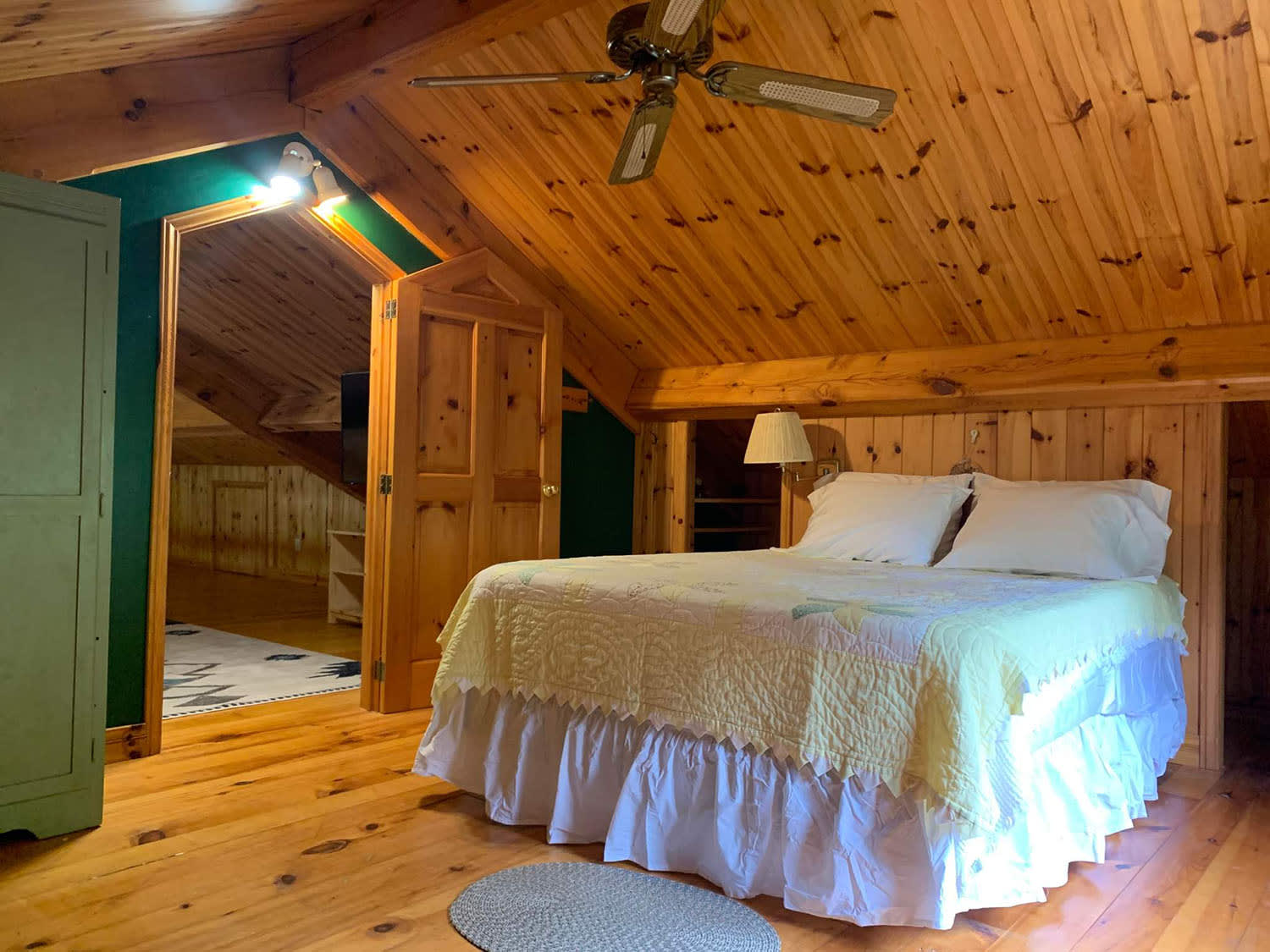A white bed in a wood-paneled room with sloped ceilings