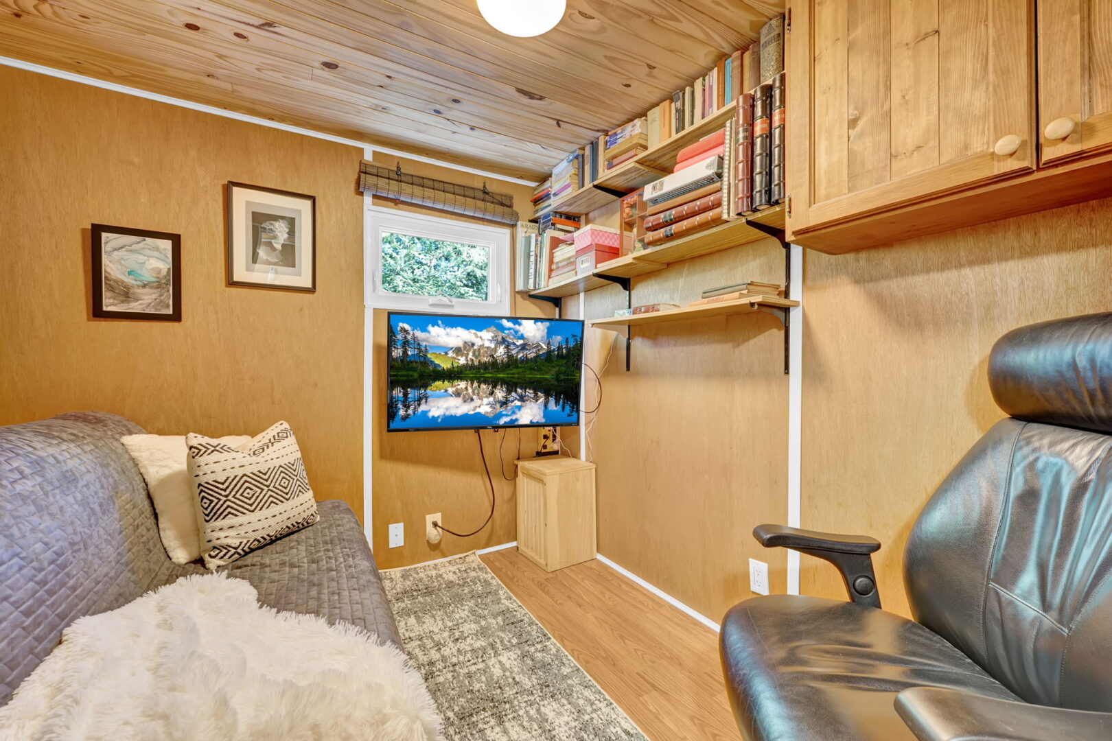 A grey couch faces a wood fall with floating bookshelves