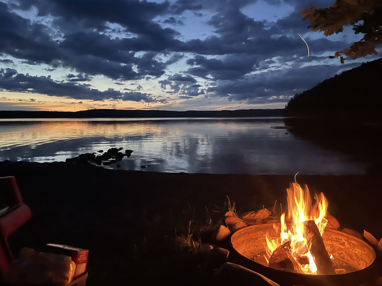 A lit fire pit at night by the lake