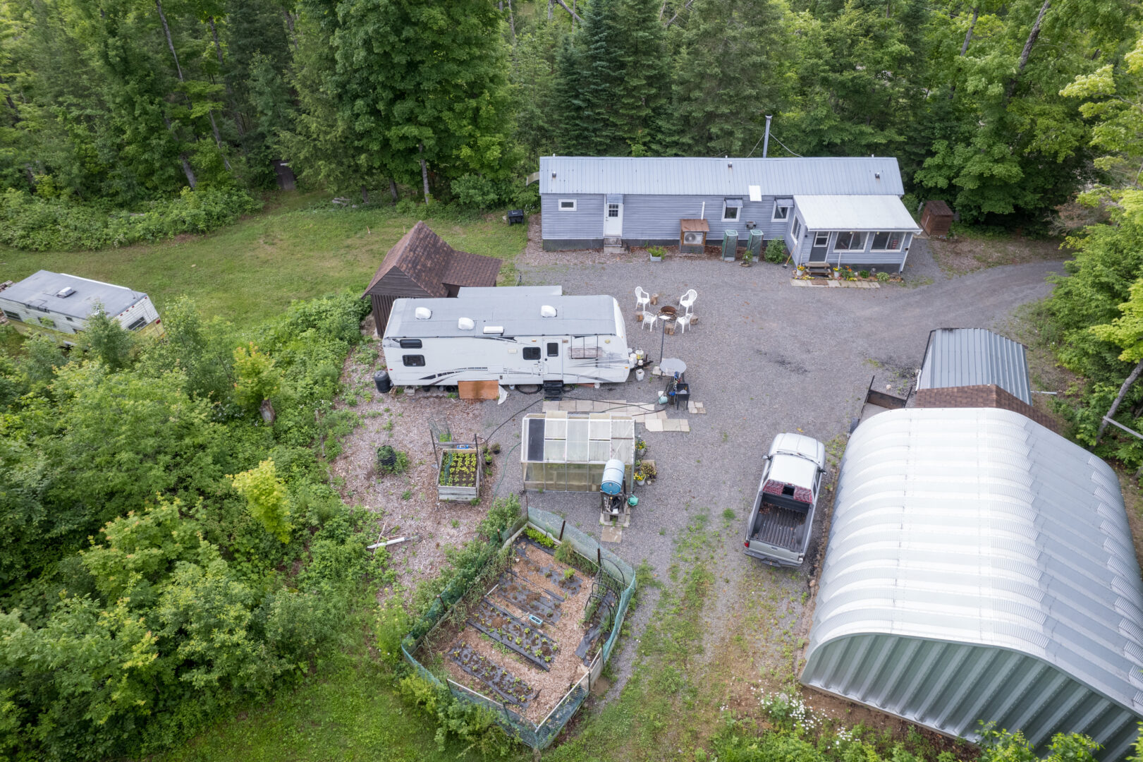 A cottage property with a main building, a mobile home, a vegetable patch, and a large garage