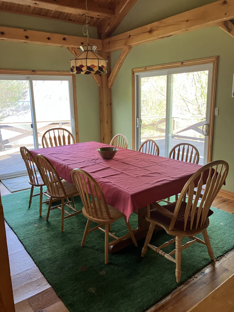 A wood dining table with a red tablecloth on a green carpet