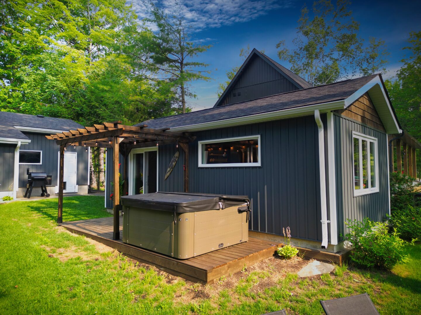 A blue-grey bunkie with a covered hot tub