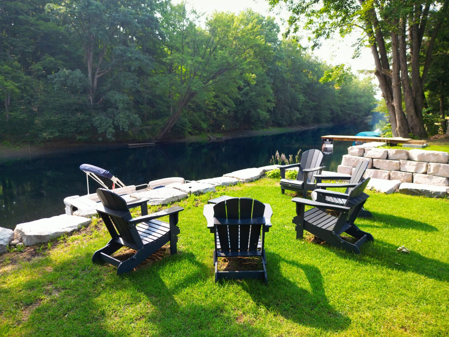 Four brown Muskoka chairs look out onto the water