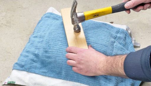 Someone using a hammer and pillow to flatten a pan