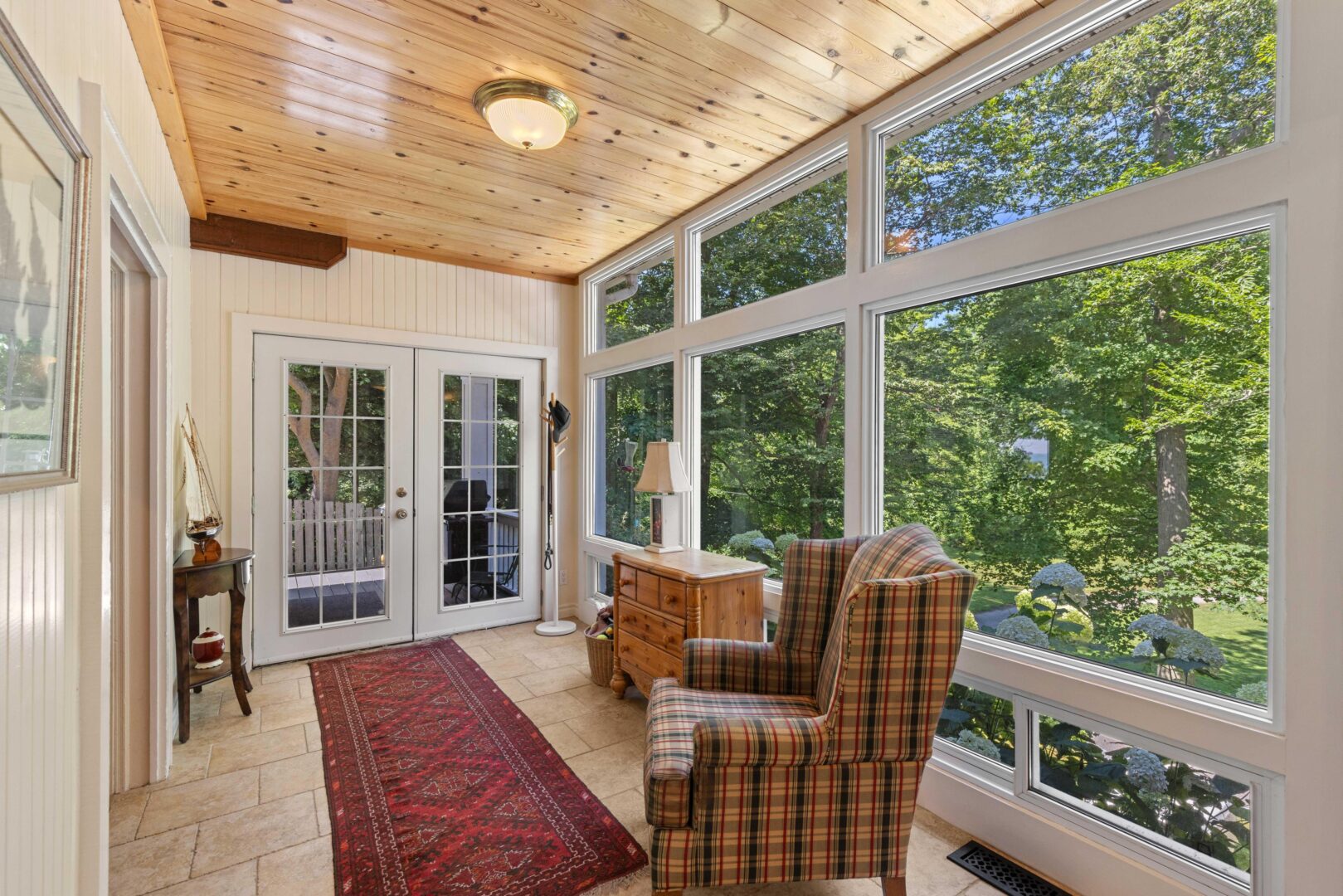 Light-filled entryway with floor-to-ceiling windows, wood ceiling, and views of the lush exterior garden