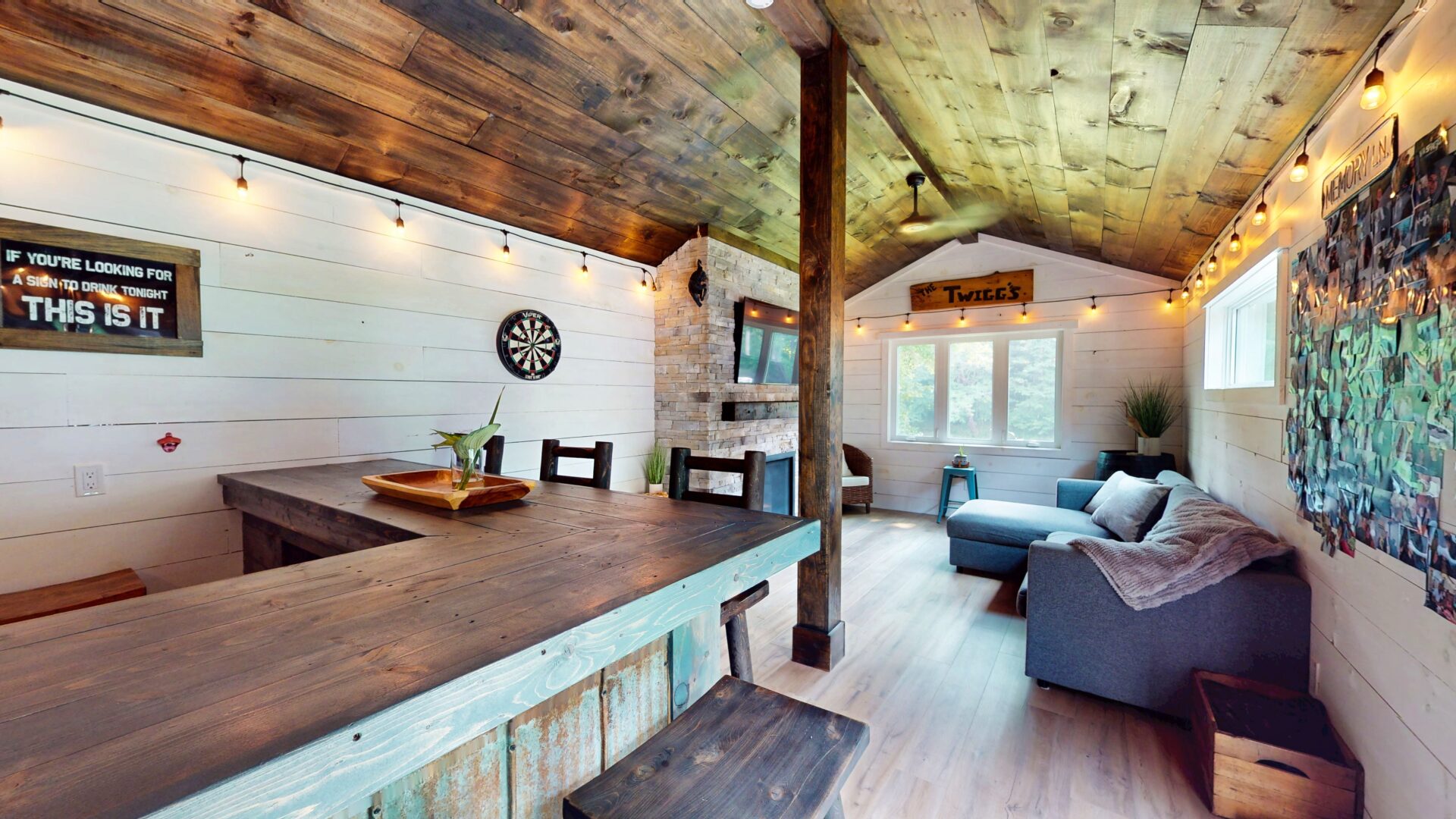 A home bar faces a blue couch and stone fireplace