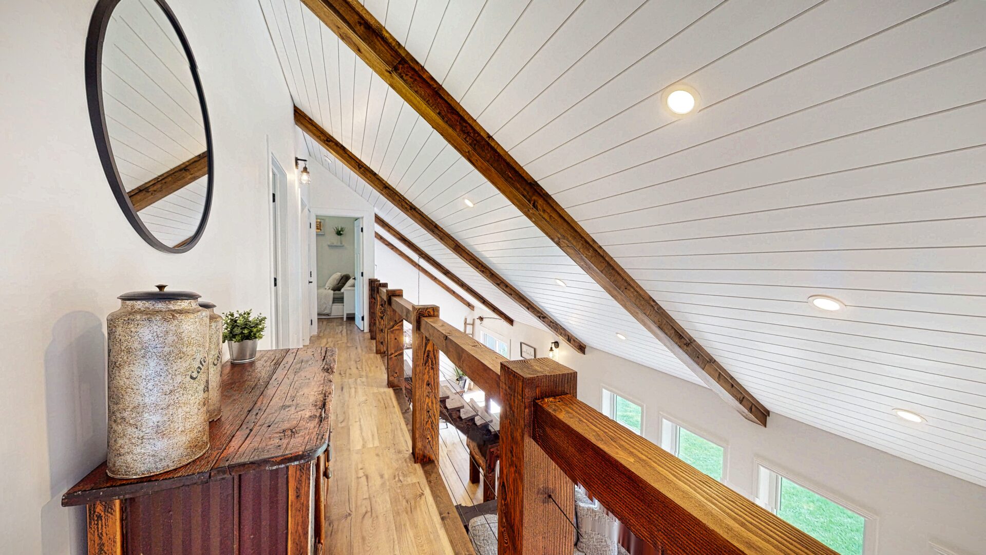 A thin wood-floored hallway with a white slanted ceiling above