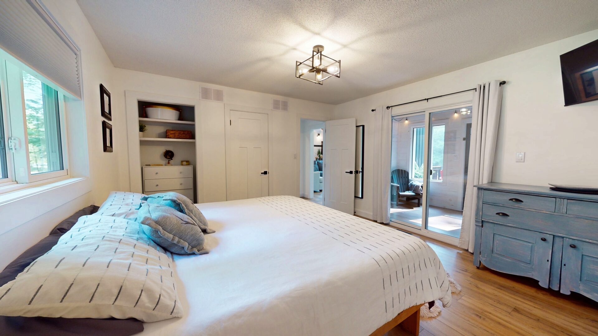 A white bed faces a closet in a white bedroom