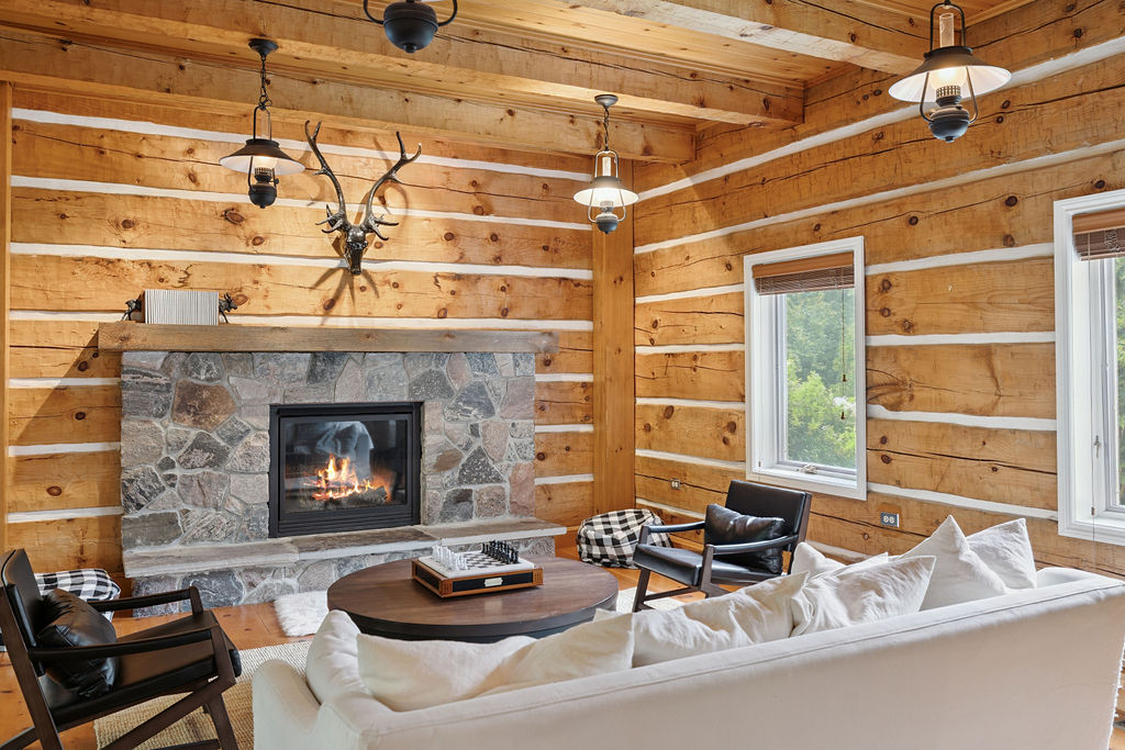 A stone fireplace faces a white couch in a wood paneled room